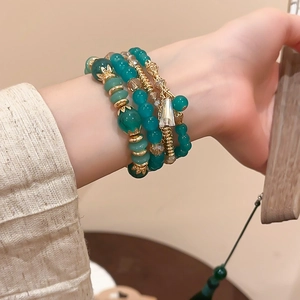 Detail of green beaded bracelet set with gold floral spacers and crystal charms