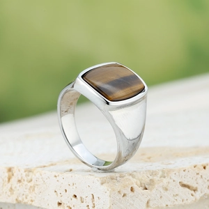 Macro shot of silver signet ring with square tiger eye stone on natural stone
