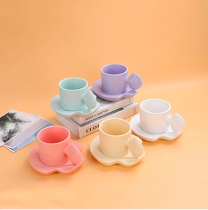 Detailed view of colorful shell-shaped ceramic coffee mugs and matching saucers