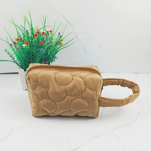 Detail of khaki quilted makeup bag with cloud pattern on white marble background