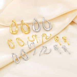 Collection of modern minimalist gold and silver earrings on champagne silk background