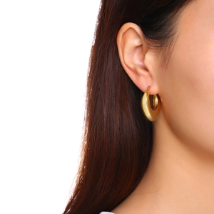 Close-up of a model wearing a polished gold chunky water drop earring with high shine finish
