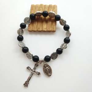 Detail of black lava stone religious bracelet with silver cross and Virgin Mary medal