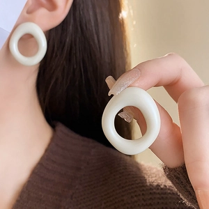 Detailed view of milky white resin round stud earring worn for elegant office look