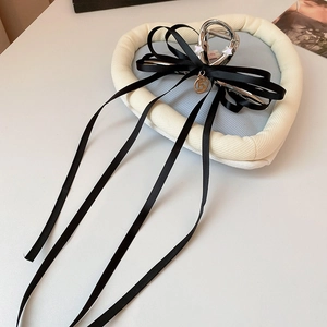 Détail de la pince à cheveux avec nœud en satin noir, rubans et pendentif numéro 5 doré