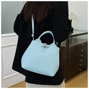 Close-up of light blue lychee pattern leather bucket bag with bamboo clasp on a model