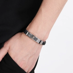 Close-up of braided leather bracelet with silver cross pendant and engraved scriptures