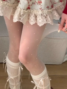 Detail of high-elasticity white polka dot tights with lace trim in a close-up shot