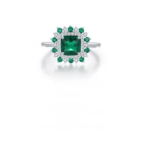 Macro shot of silver ring with emerald-cut green stone and double halo of diamonds