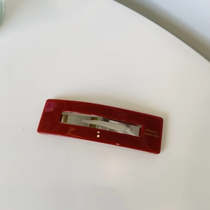 Detail of red rectangular hair clip with golden France Handmade text on white background