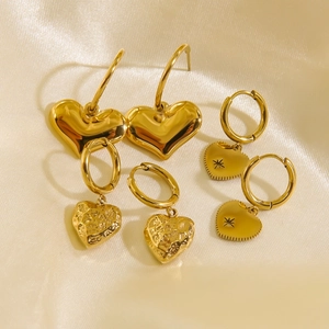 Three pairs of 14K gold heart earrings set on silk fabric including textured and smooth styles