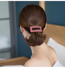Close-up of a matte pink rectangular hollow hair clip worn on the back of the head