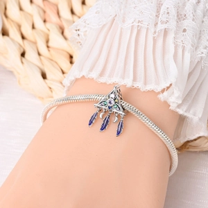 Macro detail of silver dreamcatcher charm with purple stones and enamel feathers on bracelet