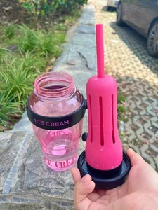 Pink high-capacity water bottle with novelty straw and Ice Cream logo in outdoor setting