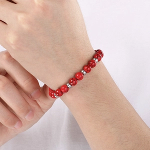 Gros plan d'un bracelet en perles rouges texturées avec entretoises en argent au poignet