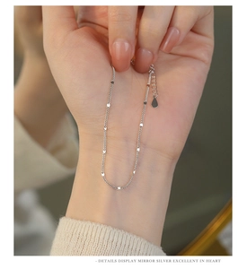 Macro detail of S925 sterling silver bracelet featuring polished oval sequins and adjustable chain