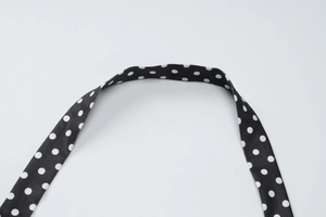 Gros plan des bretelles dos nu à pois noirs et blancs avec un tissu texturé de qualité