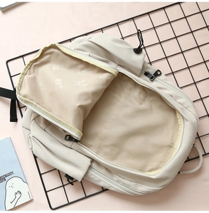 Interior view of large capacity cream backpack featuring a wide double-zipper opening