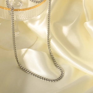 Sleek silver stainless steel curb chain necklace displayed on soft elegant silk fabric