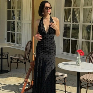 Detail of elegant black polka dot halter dress featuring a deep V-neck and ruched texture