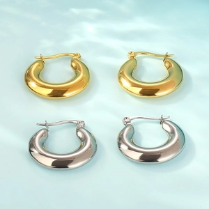 Polished gold and silver oval hoop earrings on light blue water ripple background