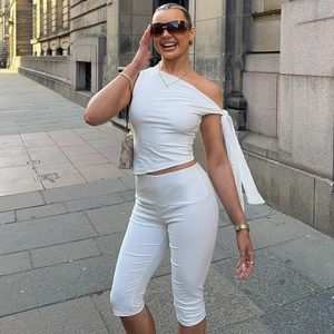 Detail von weißem One-Shoulder-Top mit Band und hoch taillierter Capri-Leggings