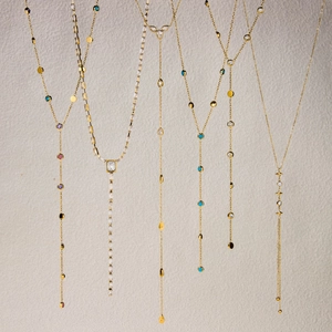 Detail of diverse 18k gold plated Y-shaped necklaces with multi-colored zircon stones