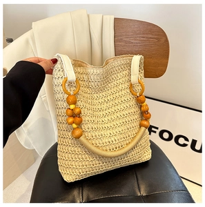 Detail of straw tote bag with wooden bead handle on a black leather chair
