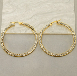 Detail of 18k gold hoop earrings with sparkling rhinestones on marble backdrop