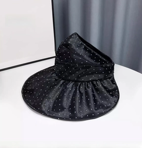 Detail of black satin sun visor with shimmering rhinestones and wide wavy brim