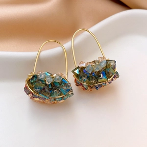 Baroque crystal flower earrings with gold wire weaving and blue-green beads on a white tray