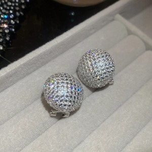 Close-up of sparkling zircon hemispherical earrings displayed in a dark grey velvet gift box