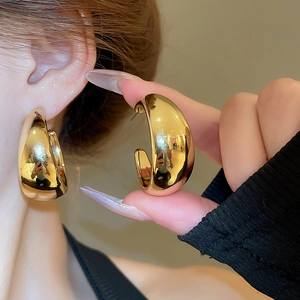 Close-up of chunky gold-plated C-shaped hoop earrings with a polished glossy finish