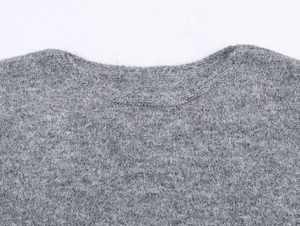 Gros plan du col du pull en tricot gris montrant la texture douce du crochet ajouré