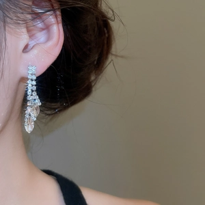 Close-up of model wearing luxury leaf-shaped marquise tassel earrings with shiny crystals