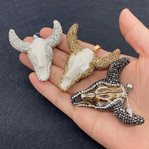 Detailed view of rhinestone-encrusted bull head pendants in white and grey resin