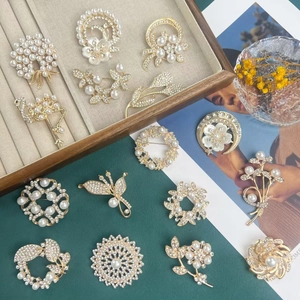 Elegant gold alloy floral brooch with pearls and crystals set on a velvet tray