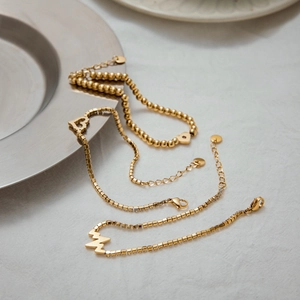 Detailed macro of gold heart and lightning pendants on a premium stainless steel chain