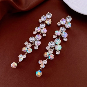 Detail of long gold tassel earrings with colorful sparkling rhinestones on brown fabric