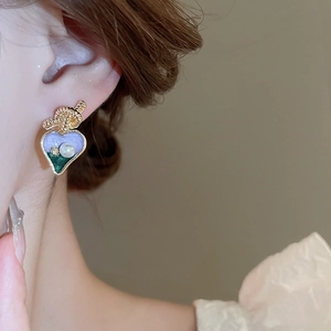 Détail d'une boucle d'oreille cœur vintage avec émail violet et perle sur modèle