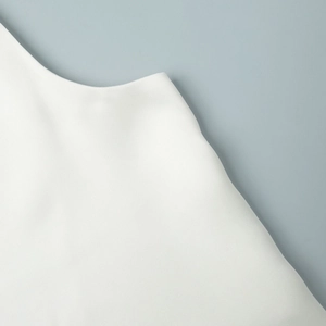 Detailed close-up of white satin tank top featuring lace trim and premium fabric texture