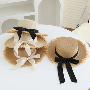 Flat top straw sun hat with black ribbon bow and fringed edge for summer beach vacation