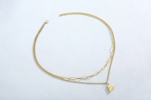 Détail d'un collier doré à double rang avec pendentif en cœur et maillons de trombone