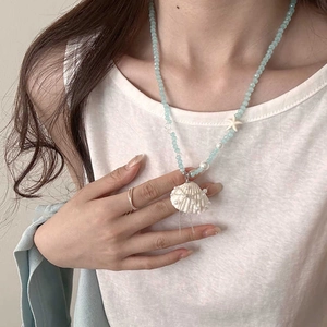 Detail of beaded sea necklace with white starfish, shell pendant and silver tassels