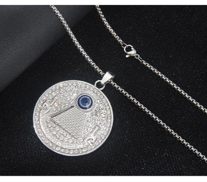 Detailed close-up of a silver rhinestone-studded Evil Eye and Pyramid pendant necklace
