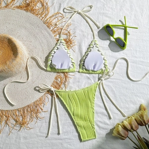 Close-up of neon green ribbed bikini with side ties and white trim on flat lay