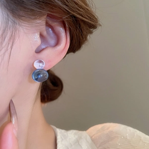 Detail of creative double-bead earrings with blue and clear resin spheres on model