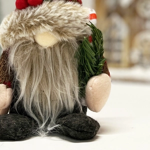 Close-up of a Christmas gnome doll with a red knit hat and lifelike pine branches