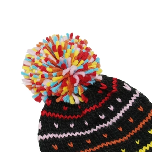 Close-up of a black knit hat featuring colorful wavy patterns and a vibrant multi-color pom-pom