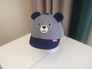 Close-up of baby striped baseball cap with cute bear ears and navy blue embroidery